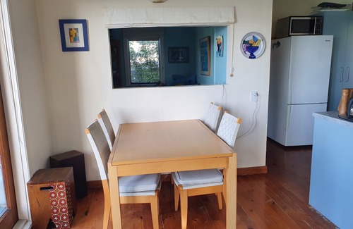 Mahurangi West Cabaña | Casa de playa icónica de Nueva Zelanda con vistas al puerto y arbustos elevados.