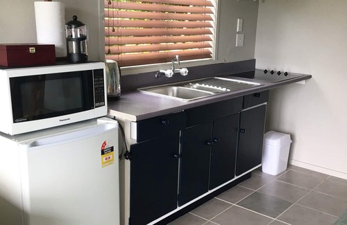 Whangaroa Chalet De Esquí | Unidad de un dormitorio con baño y sala de estar pequeña con cocina americana.