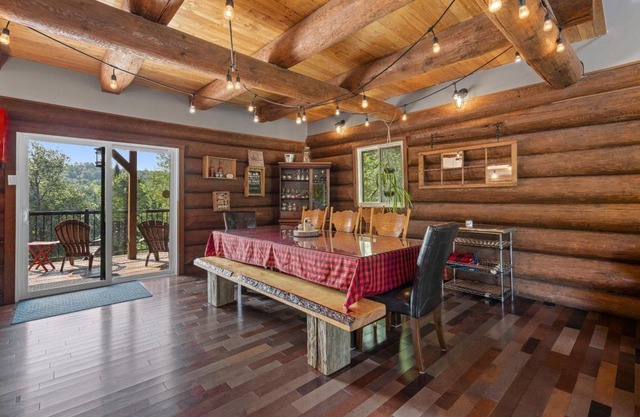 Chalet en bois rond au bord de l'eau avec spa, foyer et table de pool.