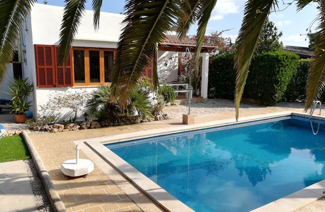 Casa vacacional con piscina y palmeras.