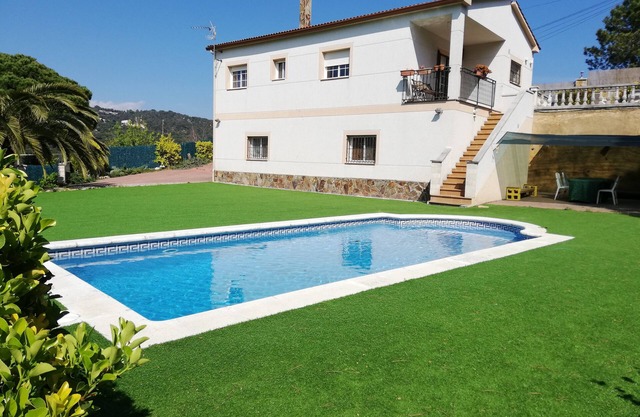 Casa con piscina privada, césped artificial, terrazas y jardines llanos.