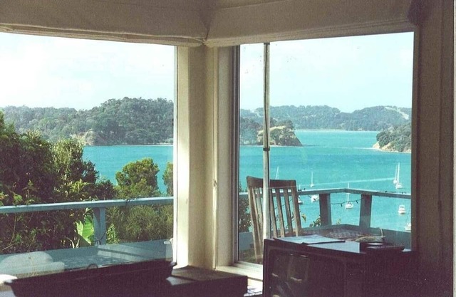 Casa de playa icónica de Nueva Zelanda con vistas al puerto y arbustos elevados.