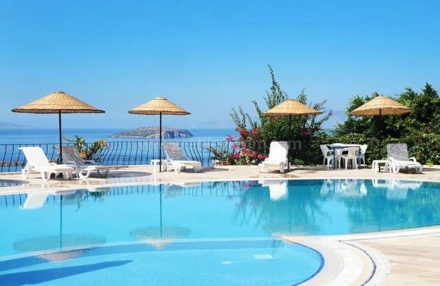 Apartamento Karya Gumusluk Bodrum con vistas al mar y piscina comunitaria.