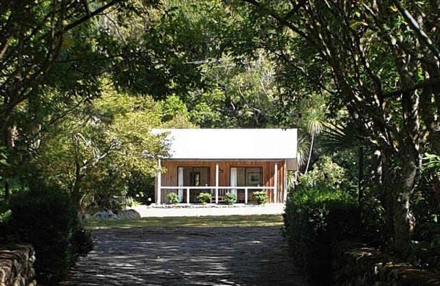 Cabaña rústica y gran bloque de cocina ubicado en un jardín nativo.