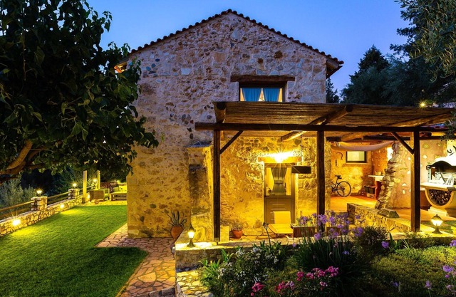 Villa de piedra escondida en árboles con piscina climatizada.