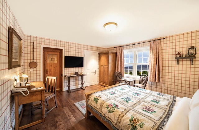 The wooden floors, vintage furniture, and tartan accents create a comfy room