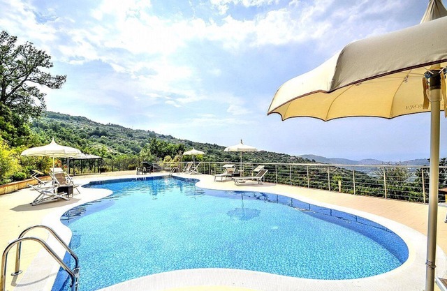 Villa Albatros A: una encantadora villa de dos pisos rodeada de vegetación.