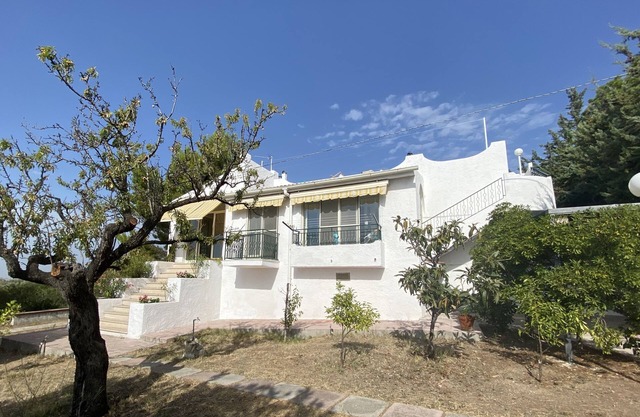 Villa con jardín con vistas al mar y olivos.